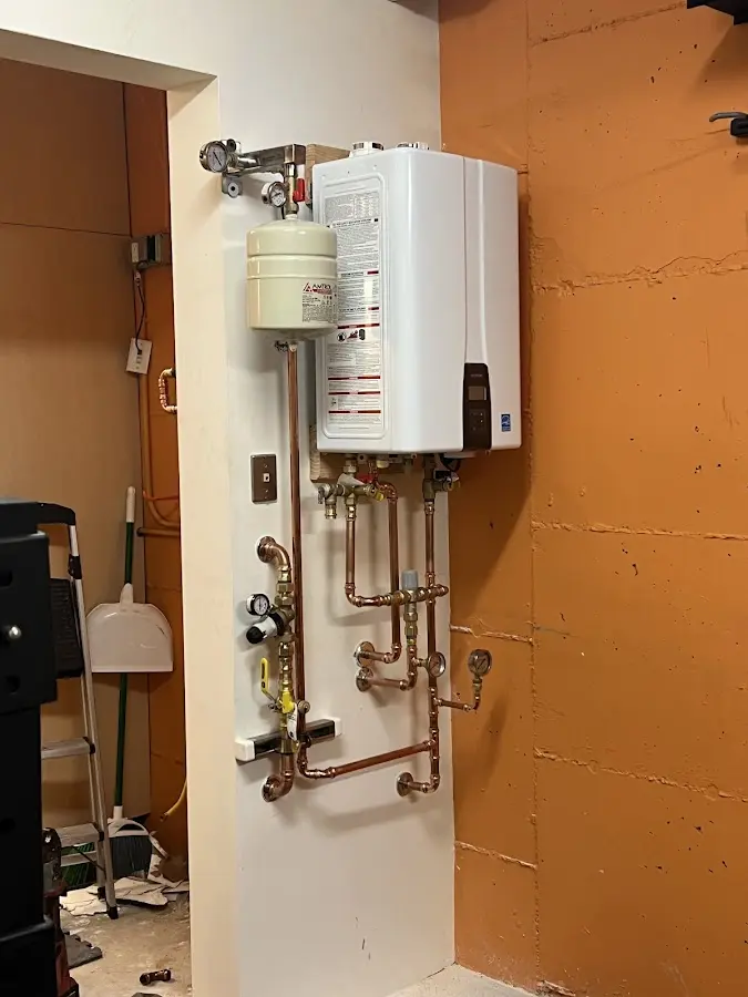 Plumbing technician inspecting water heater connections in Cumberland